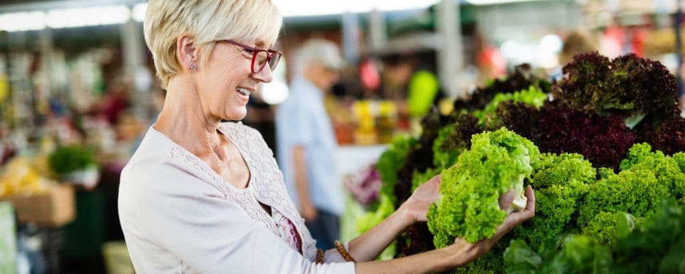 Older woman shopping for high-fiber fruits and vegetables at a grocery store