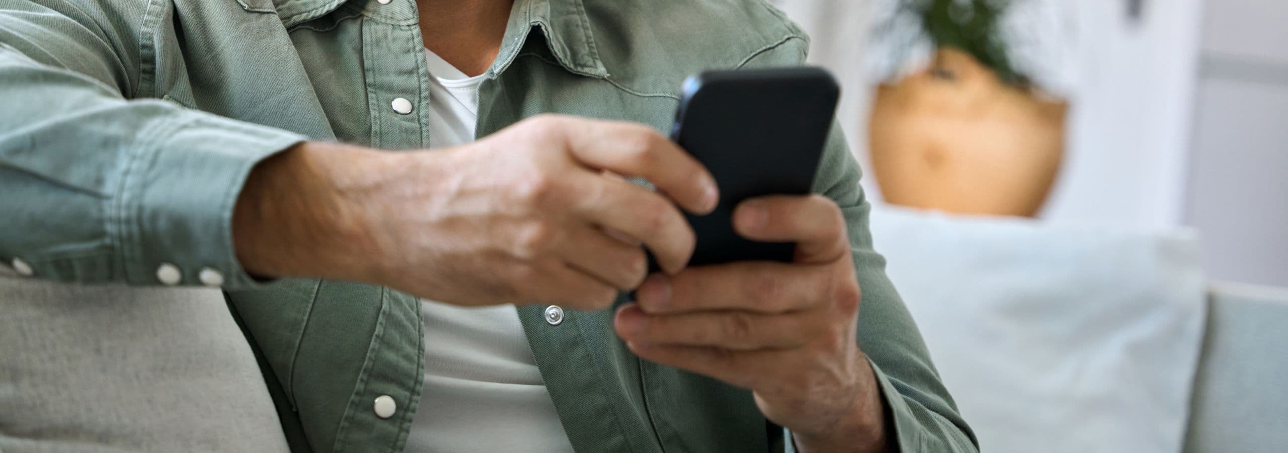 Older man sitting at home using an OTC app on his smartphone
